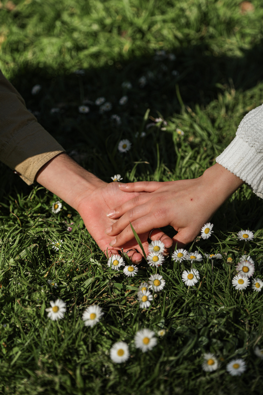 A Couple Touching Hands on Green Grass